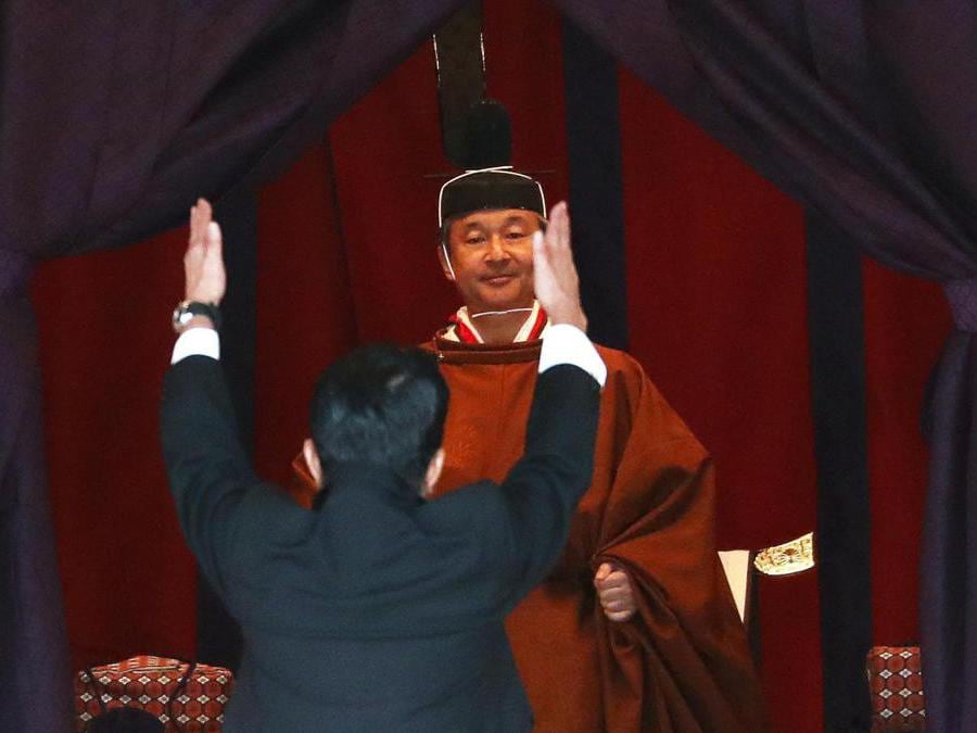 Il primo ministro giapponese Shinzo Abe (in basso) alza le mani e grida “banzai”  e applaude davanti all'imperatore Naruhito. EPA/ISSEI KATO / POOL