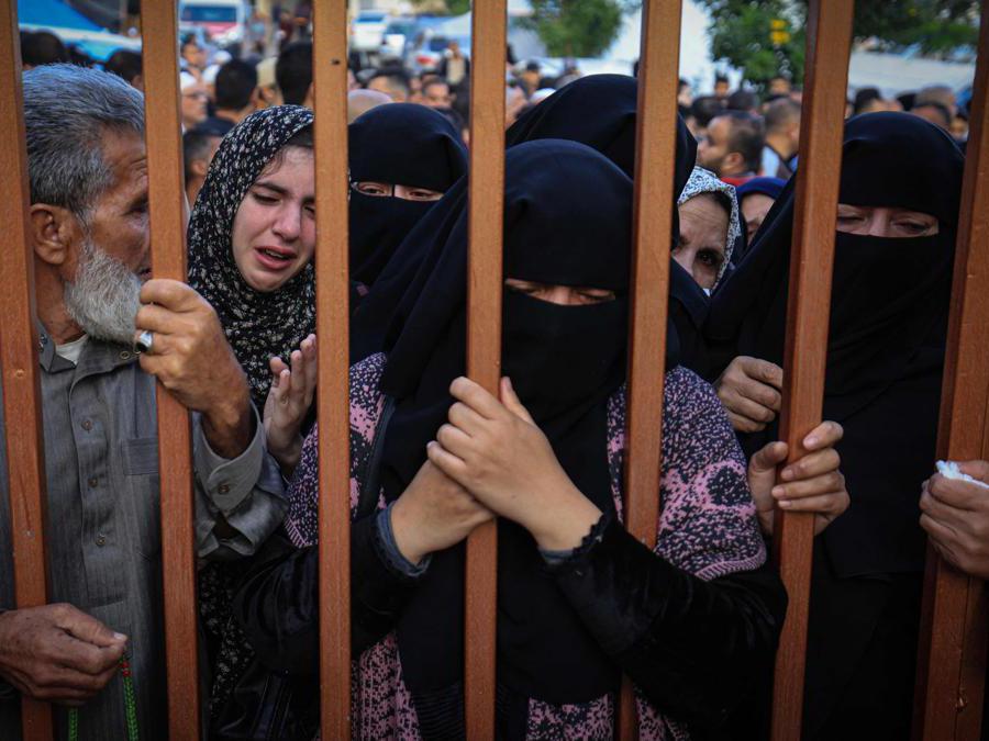 EDITORS NOTE: Graphic content / People wait their turn to identify relatives killed in Israeli bombardment on Khan Yunis in the southern Gaza strip, behind the gate leading to the morgue of the Al-Nasr hospital where the bodies of victims are laid, out on November 19, 2023, as battles continue between Israel and the Palestinian militant group Hamas. (Photo by Mahmud HAMS / AFP)