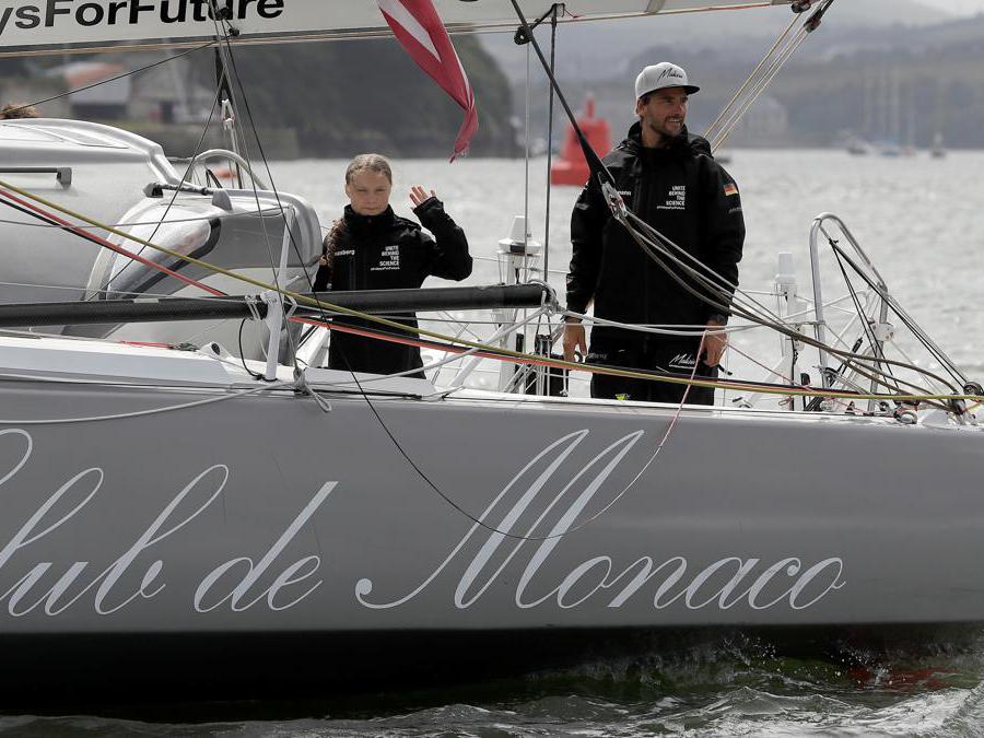 L'attivista svedese per il clima adolescente Greta Thunberg saluta dalla barca  Malizia II accanto al velista tedesco Boris Herrmann, mentre inizia il suo viaggio.  Kirsty Wigglesworth/Pool via REUTERS