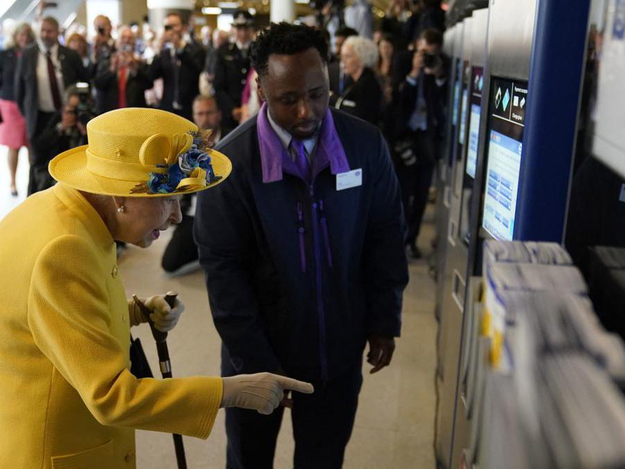 La regina Elisabetta II utilizza un distributore automatico di biglietti Oyster Card durante la sua visita alla stazione di Paddington a Londra (Andrew Matthews/AFP)