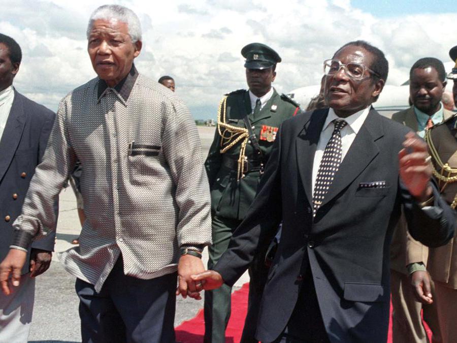 Il presidente Robert Mugabe dello Zimbabwe (destra)  con il suo omologo sudafricano Nelson Mandela che lo saluta al suo arrivo nel paese il 13 dicembre 1998. REUTERS/Howard Burditt/File Photo