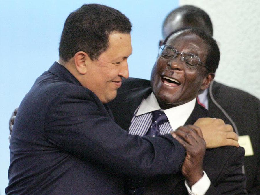 In questa foto del file scattata il 17 ottobre 2005 il presidente venezuelano Hugo Chavez (sinistra) abbraccia l'allora presidente dello Zimbabwe, Robert Mugabe (destra), dopo il discorso di Mugabe durante una conferenza sulla fame in occasione del 60 ° anniversario dell'Organizzazione delle Nazioni Unite per l'alimentazione e l'agricoltura nella sede della FAO a Roma. (Photo by GIULIO NAPOLITANO / AFP)