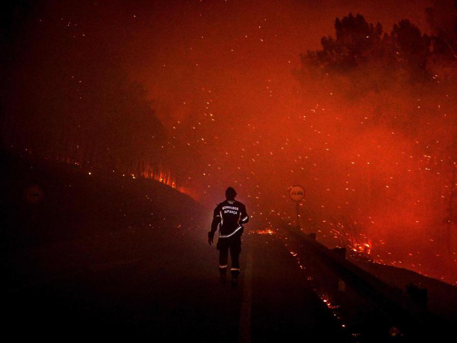 Un vigile del fuoco cammina sulla strada con un flash durante un incendio a Manteigas, nel Portogallo centrale (Patricia De Melo Moreira/Afp) 