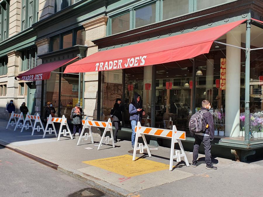 La gente fa la fila davanti a un supermercato Trader Joe, distanziati l'uno dall'altro. In pochi indossano la mascherina.