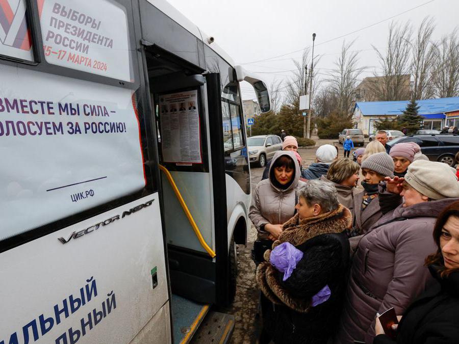 Gli elettori si riuniscono fuori da un seggio elettorale mobile situato in un autobus, l’ultimo giorno delle elezioni presidenziali russe , a Makiivka (Makeyevka) nella regione di Donetsk, Ucraina controllata dalla Russia, March 17, 2024. REUTERS/Alexander Ermochenko