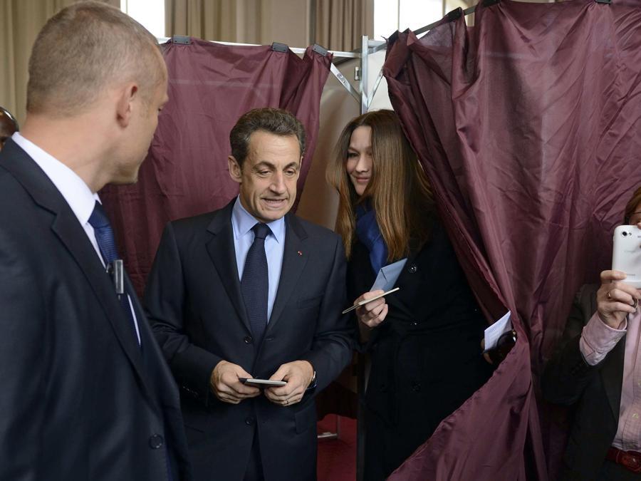 Nicolas Sarkozy e sua moglie Carla Bruni-Sarkozy escono dalla cabina elettorale dopo aver votato al primo turno delle elezioni presidenziali francesi nel 2012. (AP Photo/Eric Feferberg, Pool)