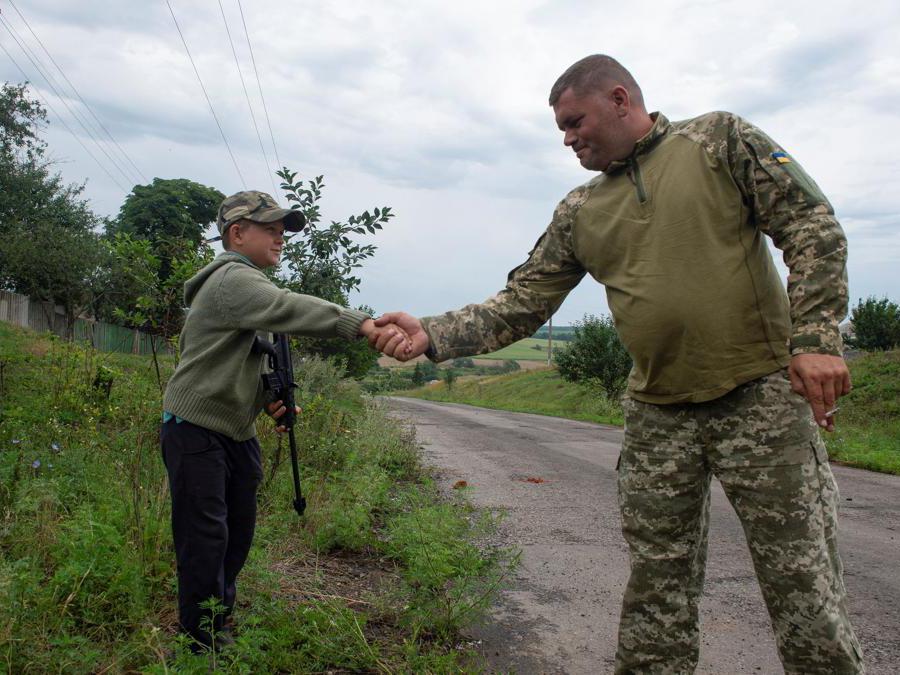 Regione di Kharkiv , un bambino ucraino armato di fucile stringe la mano a un soldato (REUTERS/Sofiia Gatilova)