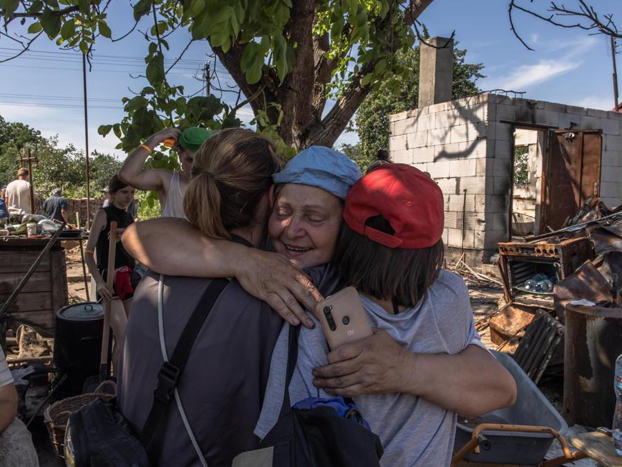 Una donna ucraina abbraccia dei giovani volontari addetti allo sgombero dei detriti prodotti dai bombardamenti russi(EPA/ROMAN PILIPEY)