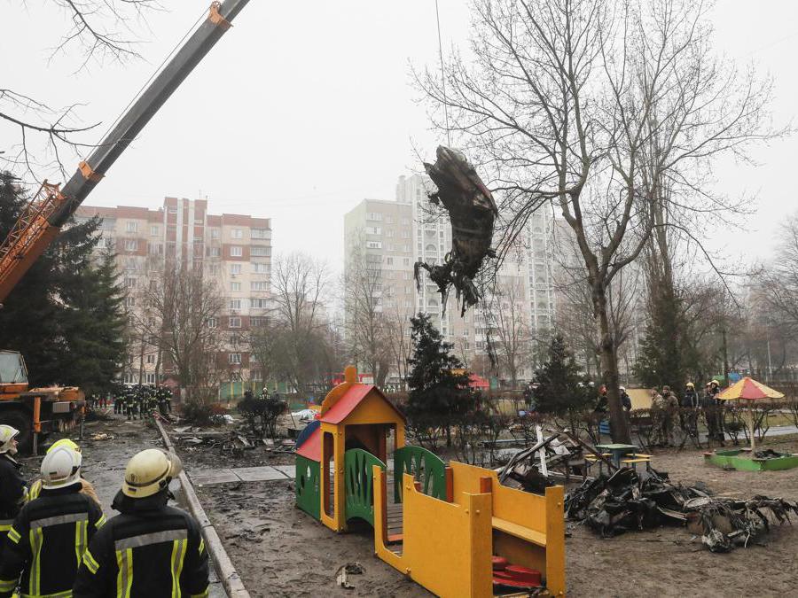 Una parte di un elicottero precipitato vicino a un asilo viene rimossa a Brovary, fuori dalla capitale Kiev,  durante l’invasione russa dell’Ucraina. Diciotto persone, tra cui il ministro dell’Interno ucraino e tre bambini, sono rimaste uccise in un incidente in elicottero vicino a un asilo fuori Kiev (Epa/Sergey Dolzhenko) 