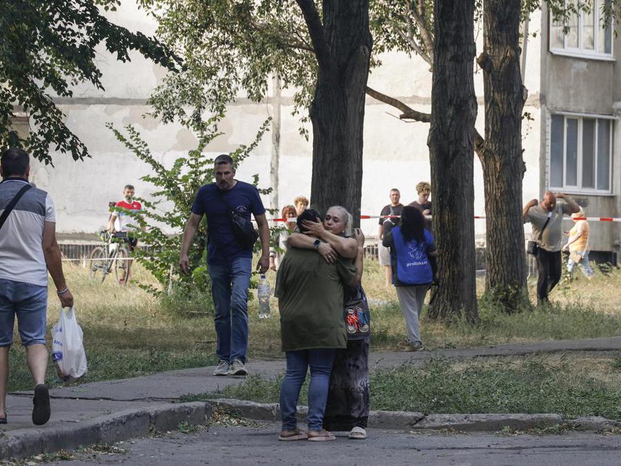 La gente del posto reagisce vicino al sito di un edificio residenziale di 12 piani danneggiato a seguito di un attacco missilistico a Kharkiv, nel nord-est dell’Ucraina. EPA/SERGEY KOZLOV