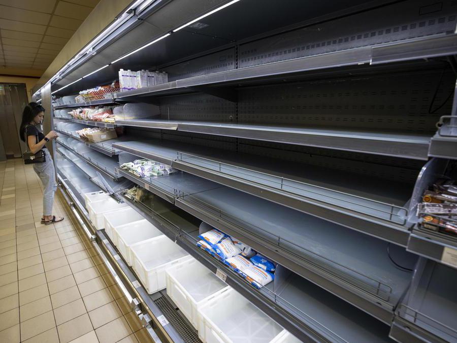 Una persona compra in un supermercato dove gli scaffali sono quasi svuotati (EPA/Orlando Barria)