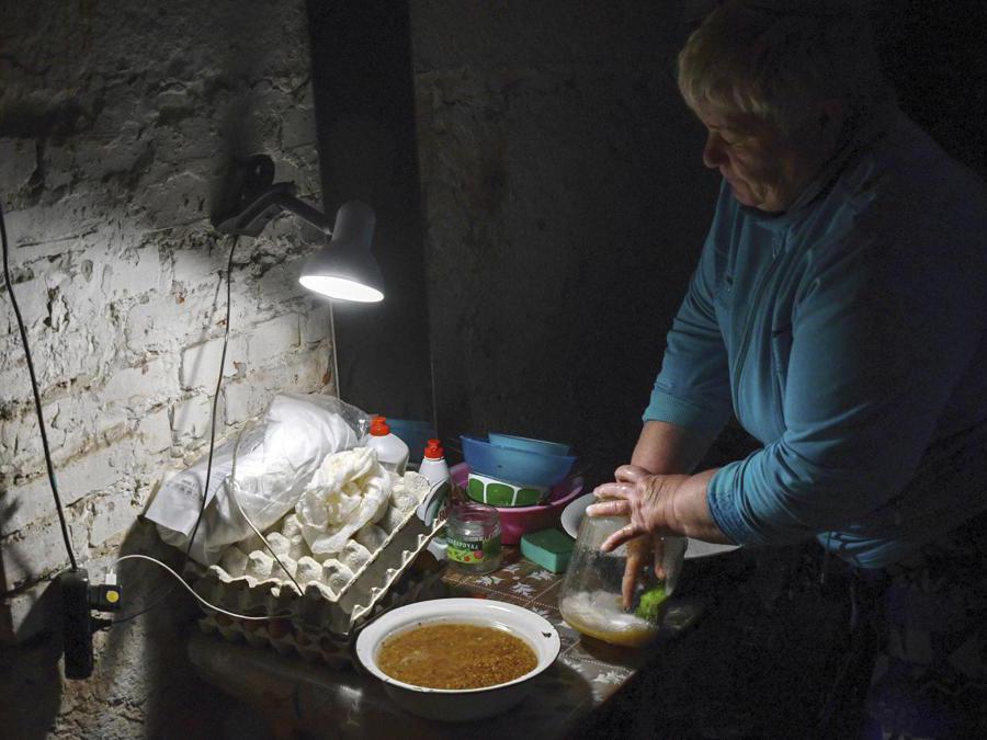 Una donna ucraina lava i piatti nel seminterrato di un edificio utilizzato come rifugio antiaereo a Soledar, nella regione di Donetsk, in Ucraina  (AP Photo/Andriy Andriyenko)