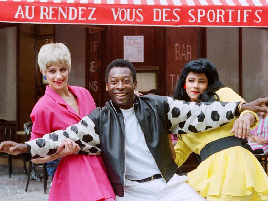 Il più grande calciatore di sempre, Edson Arantes do Nascimento, meglio conosciuto come “Pelé”, tre volte vincitore della Coppa del Mondo del Brasile (1958, 1962, 1970), posa l’8 agosto 1987 a Parigi con due comparse mentre si esibisce per un filmato pubblicitario per Società francese del Loto. (Michel Clement/Afp)