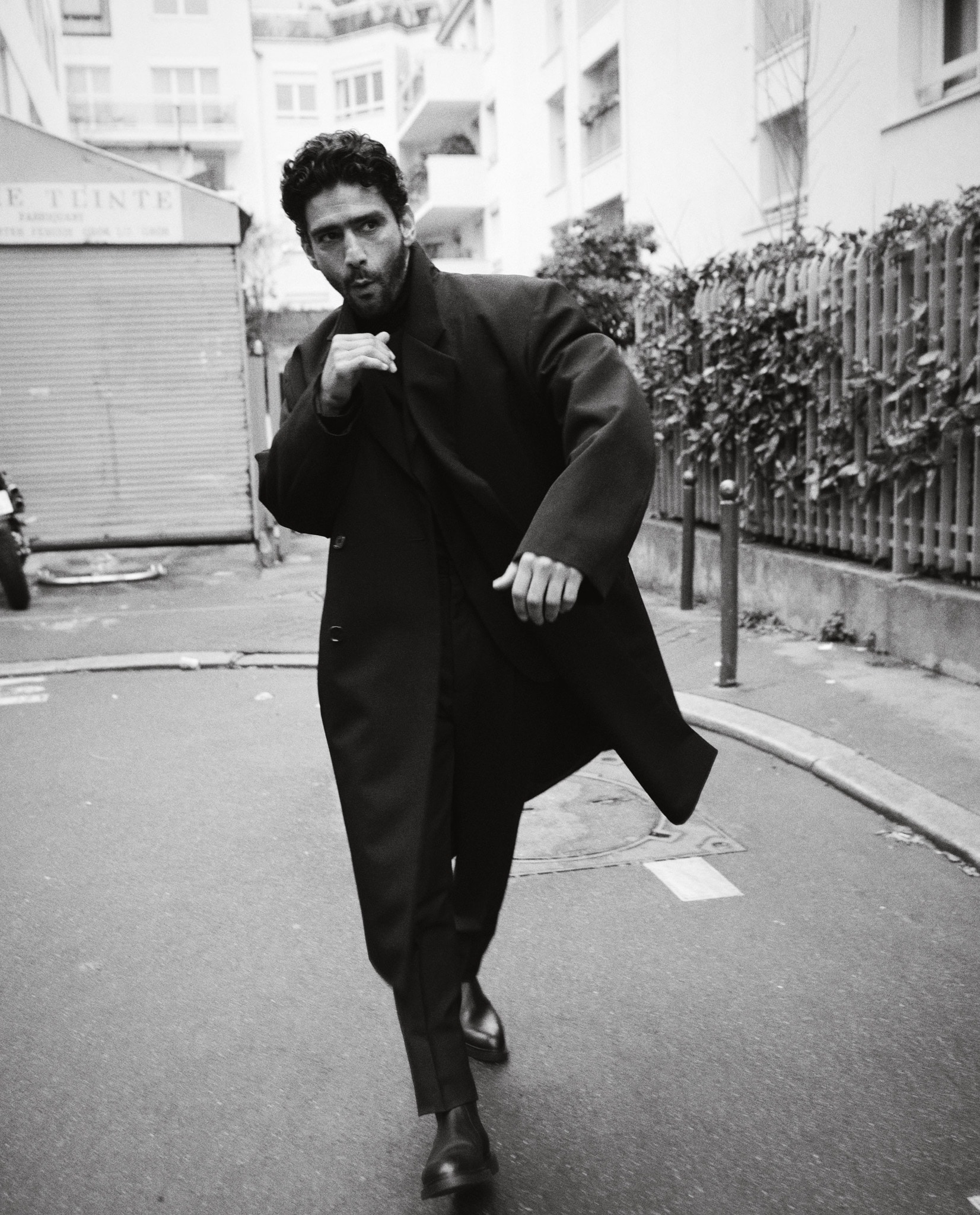 Salim Kechiouche indossa un cappotto di gabardine, LEMAIRE (1.100 €). Pantaloni in lana mohair, PRADA (1.495 €). Stivaletti in pelle, J M WESTON (800 €). Per tutte le immagini: Foto di Antoni Ciufo. Styling di Isabelle Kountoure.